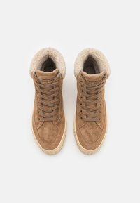 Brune semskede høyhælte sneakers med beige kunstpelsfôr, rund tå, flat kremgummisåle, og snøring foran.