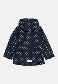 Giacca a pois blu navy con cappuccio, vita elastica e maniche lunghe. Presenta una texture liscia e impermeabile e un'etichetta bianca semplice sul retro.