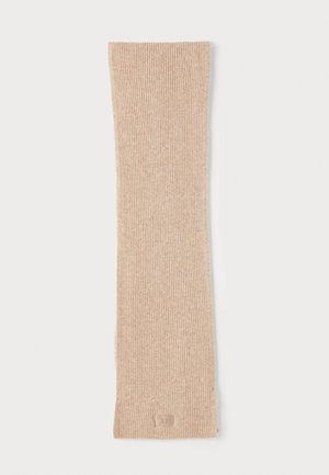 Beige ribbed scarf made of soft material, featuring a subtle texture and a small logo patch at the bottom. Long, rectangular shape.