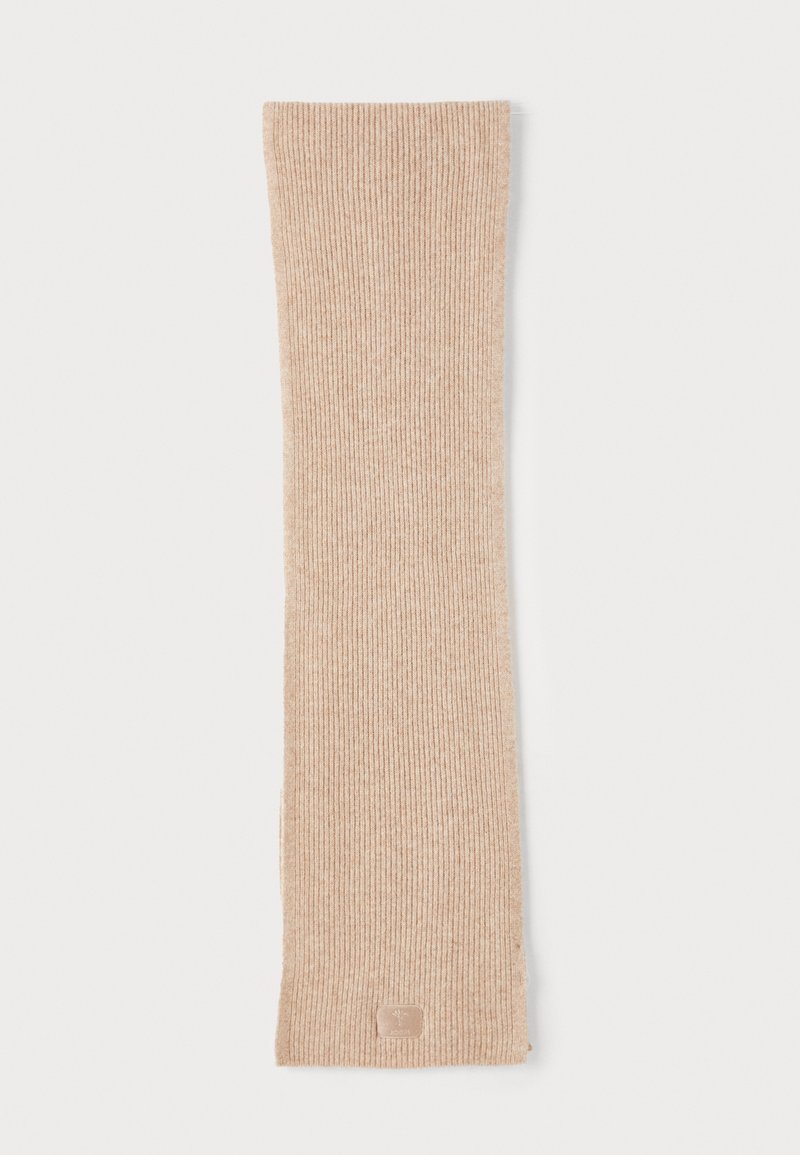 Beige ribbet tørklæde lavet af blødt materiale, med en subtil tekstur og et lille logo-patch nederst. Lang, rektangulær form.