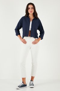 Navy cropped button-up shirt, lightweight fabric, long sleeves. Paired with white high-waisted jeans and navy sneakers, featuring white laces.