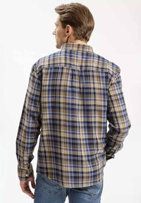 Koszula w kratę z flaneli w kolorach niebieskim, brązowym i beżowym, z długimi rękawami, zapinana na guziki z detalem w formie części z tyłu.