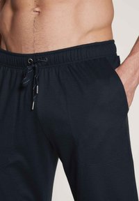 Marineblauwe joggingsbroek van zachte stof, met een elastische tailleband met trekkoord, zijzakken en een relaxed fit.