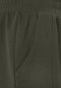 Dark green cotton pants featuring a smooth texture, a waistband with elastic, and side pockets with subtle stitching details.