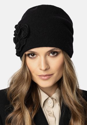 Black felt hat with a soft texture, featuring a decorative black fabric flower on the side. Form-fitted design with a draped silhouette.