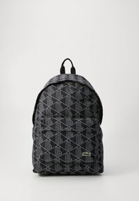 Rucsac din material durabil, cu un model geometric negru și gri, bretele captușite și un mic logo verde ca accent.