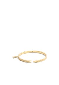 Brazalete de metal dorado con un diseño texturizado que presenta patrones lineales, extremos abiertos y un pequeño charm decorativo.
