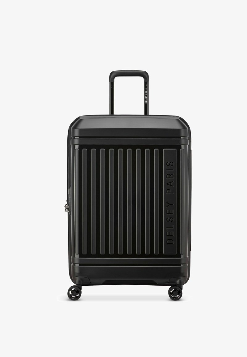 Maleta negra de plástico duro con surcos verticales, asa extensible y cuatro ruedas. Presenta el logotipo en relieve "Delsey Paris" en la parte delantera.