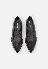 Ballerine in pelle nera con design a punta. L'interno presenta una texture trapuntata. Logo visibile sulle sole interne.