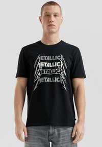 Schwarzes Baumwoll-T-Shirt mit einem großen, metallisch-silbernen "Metallica"-Grafik in fetter Schrift. Kurze Ärmel und klassische Passform.