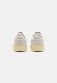 Vita lädersneakers med ljusgråa mockaaccenter, med en strukturerad gummisula och prägling av "VEJA"-logotypen på hälen.