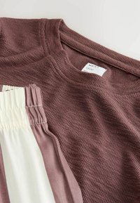 Maglietta marrone a costine con scollatura rotonda, abbinata a un tessuto crema con dettagli arricciati in vita. Etichetta visibile all'interno.
