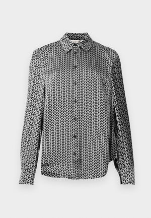 Chemise boutonnée en noir et blanc avec un motif de flèches répétitif, manches longues et col. Fabriquée en tissu léger.