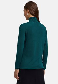 Türkiser Pullover mit Mock-Turtleneck aus weichem Strickstoff, mit langen Ärmeln und lockerer Passform sowie feiner Textur.