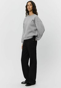 Gray fleeced sweatshirt with a black bow design on the left chest, paired with black wide-leg pants featuring white polka dots.