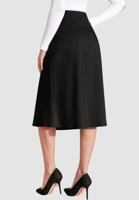 Faldas midi negras en línea A, confeccionada con una tela suave y fluida y una cinturilla alta, combinada con tacones altos negros. Diseño minimalista, sin patrones.