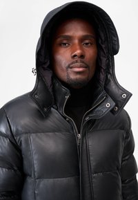 Schwarze gesteppte Lederjacke mit Kapuze, ausgestattet mit Reißverschluss, Druckknöpfen und gesteppter Textur für Wärme und Stil.