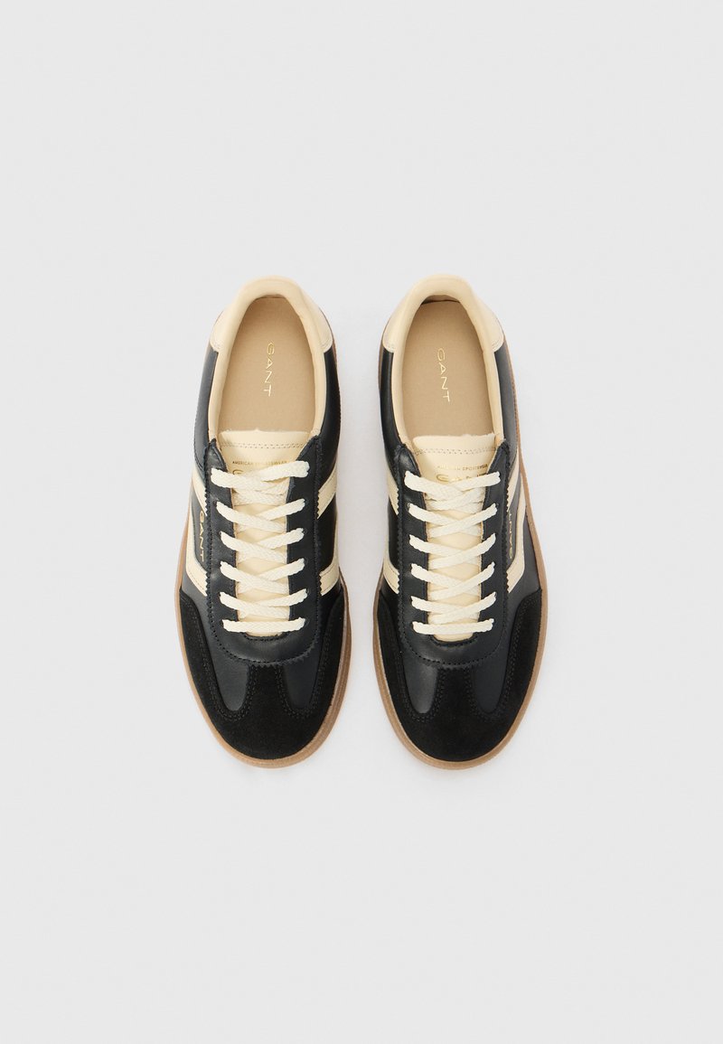 Baskets noires et beiges avec une texture en cuir lisse et en daim. Design classique avec un bout rond, un système de laçage à l'avant et une semelle en caoutchouc transparent.