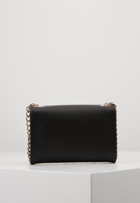 Borsa nera con superficie texturizzata, tracolla a catena, forma rettangolare e design minimalista. Presenta dettagli in metallo color oro.