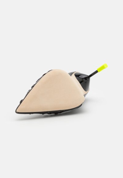 Black and beige shoe with a sleek design, featuring a pointed toe, smooth surface, textured material, and a bright yellow accent on the heel.