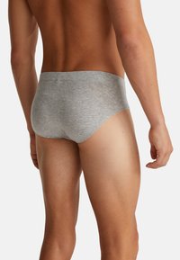 Šedé bavlněné trenýrky s hladkým povrchem a elastickým pasem, zobrazené ze zadní strany. Materiál je lehký a přiléhavý.