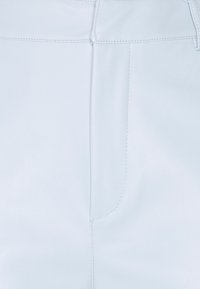 Světle modré kalhoty z umělé kůže s hladkou texturou, přizpůsobenými švy a přiléhavým střihem, s předními kapsami.