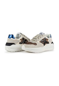 Beige sneakers featuring a leopard print accent, black cross design, silver and blue detailing, and a chunky white sole.