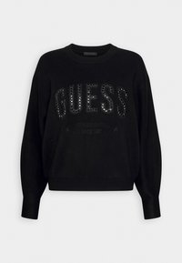 Schwarzer Pullover mit übergroßer Passform, gerippten Bündchen und Saum. Verfügt über ein glitzerndes "GUESS"-Logo und zusätzlichen Text in subtil erhobenem Stil.