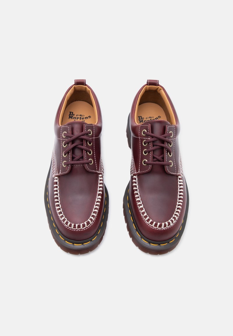 Pair of dark red leather Dr. Martens shoes with white stitching, black soles, yellow stitching, and lace-up closure viewed from above.