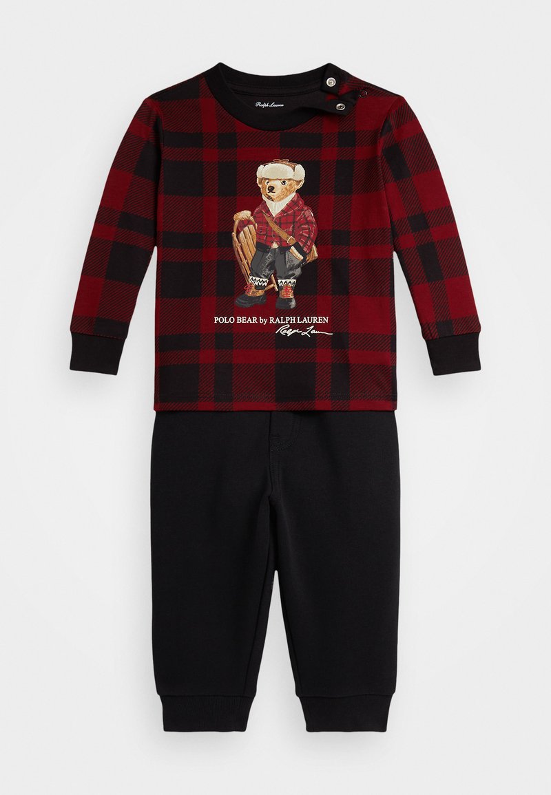 Rød og svart rutet skjorte med lang erme og bjørnegrafikk, sammen med svarte bukser; har knappelukking ved skulderen. Mykt og behagelig stoff.