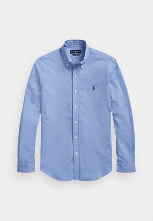 Lyseblå langærmet skjorte med knapper foran, knappet krave og en lille mørk broderet logo på venstre bryst.