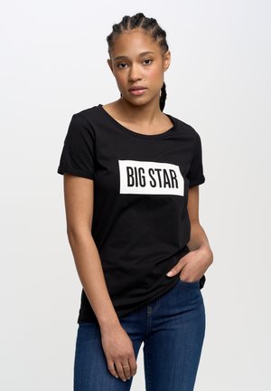 Juodas medvilninis marškinėlis su baltu stačiakampiu "BIG STAR" logotipu. Trumpomis rankovėmis ir apvaliu iškirpimu. Dėvimas su mėlynomis džinsomis.