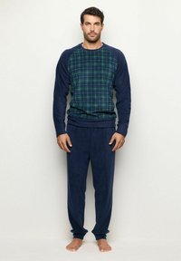 Granatowe piżamy z polarowego materiału z wzorem w kratę w odcieniach zieleni i niebieskiego na górze. Długie rękawy i elastyczny pas w spodniach.