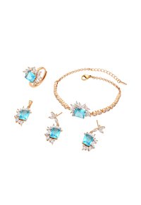 Set di gioielli in tonalità oro composto da anello, bracciale e orecchini, impreziosito da grandi gemme blu e accenti floreali in pietre trasparenti.