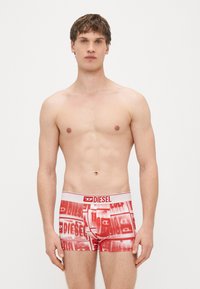 Boxer rossi con stampa integrale del nome del marchio "DIESEL" in bianco, con fascia in vita bianca e dettaglio del logo rosso.