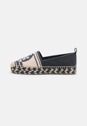 Chaussure espadrille à enfiler bleu marine et beige avec semelle tressée, bout en tissu présentant un motif circulaire, et talon en cuir avec languette de maintien.