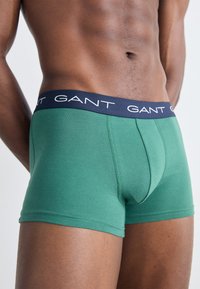Boxer ajustados de algodón verde elástico con una cinturilla del logo de GANT en color marino y un diseño ceñido, que presenta una costura central y una textura suave.