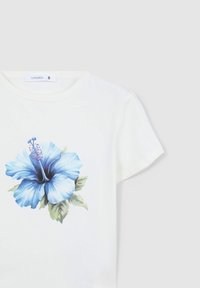 T-shirt in cotone bianco con un grande stampa di fiore hibiscus blu e foglie verdi. Collo rotondo e maniche corte.