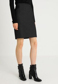 Svart texturerad kjol med A-linjeform, med hög midja och sidofickor, i kombination med svarta ankelstövlar med nitar.