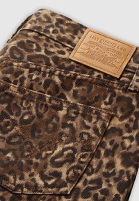 Leopardprint denim stof heeft een bruin en zwart kleurenschema. Inclusief een leren label met de merknaam aan de bovenkant van de achterzak.
