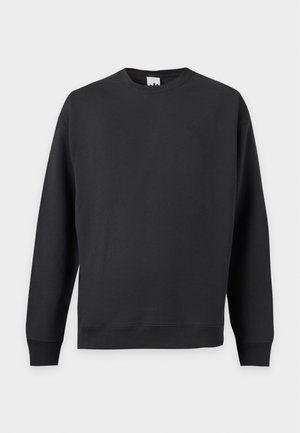 Sweat-shirt noir uni à manches longues, col rond, avec poignets et ourlet côtelés, présenté sur un fond gris clair uni.