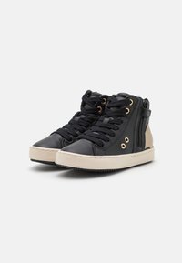 Musta korkeavartiset tennarit, jotka on valmistettu nahasta, vaaleanbeigellä korostuksella, teksturoitu pinta, mustat nauhat, sivuvetoketju ja kumipohja.