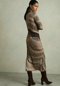 Rochie cu mâneci lungi, având un model cu imprimeu de șarpe în tonuri pământii, confecționată dintr-un material elastic, cu o fanta pe lateral și o siluetă ajustată.