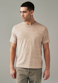 Ljusbrun kortärmad T-shirt i textuerat material, med rund halsringning och en liten broderad logotyp på bröstet.