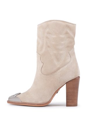 Stivaletto beige in suede con fusto decorato, punta tonda, punta metallica e tacco in legno a piramide.