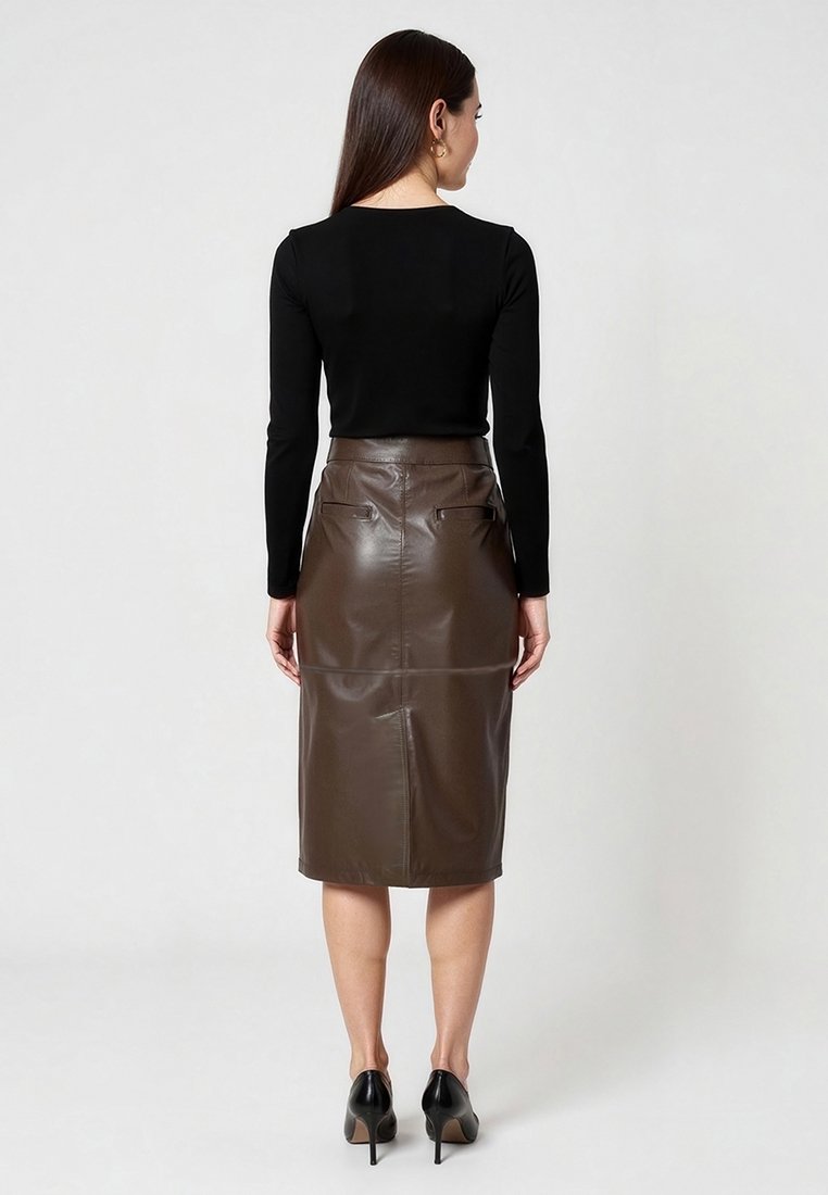 Jupe crayon en simili cuir marron, taille haute, avec poches arrière. Haut noir ajusté à manches longues et chaussures à talons hauts noires.