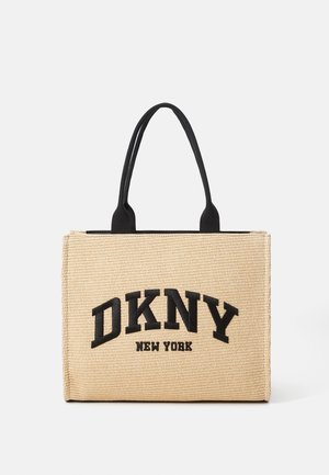 Béžová taška přes rameno s tkanou texturou, černými doplňky a výrazným logem "DKNY NEW YORK". Dva černé úchyty pro snadné nošení. Obdélníkový tvar.
