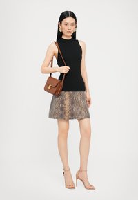 Top negru cu nervuri, fustă cu model piton, geantă de umăr bej, tocuri cu barete bej, texturi netede, siluetă ajustată.