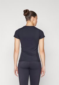 Camiseta atlética preta ajustada com mangas curtas, textura suave e detalhes de costura discretos, combinada com leggings ajustadas correspondentes.