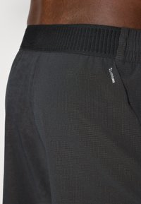 Sorte sportsshorts med et struktureret mønster, der har en åndbar sort elastisk talje og et lille hvidt "Climacool" logo på siden.